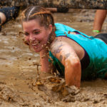 Participant smilling while crawling in the mud