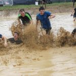 team boys running muddy water