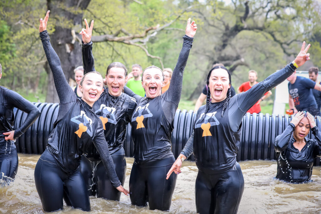 four girls water obstacle Tough Mudder outside in summer